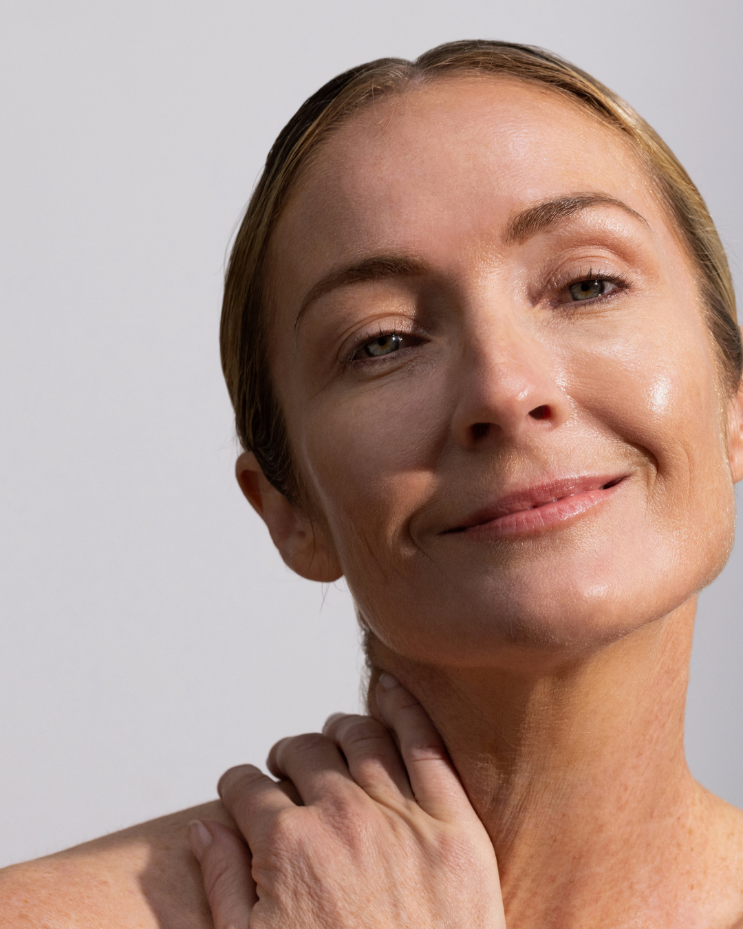 Woman touching her cheek with hydrated, healthy looking summer skin.